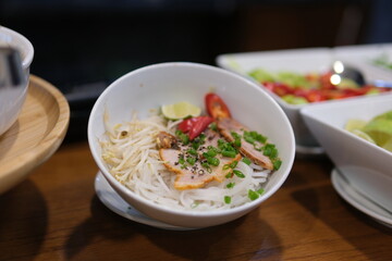 Traditional Vietnamese soup Pho bo with herbs, meat, rice noodles, broth. Pho bo in bowl with chopsticks, spoon. Space for text. Top view. Asian soup Pho bo on wooden table background. Vietnamese soup