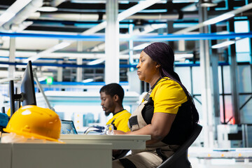 Technician monitors manufacturing data on pc in solar panel factory, employee finetunes equipment...