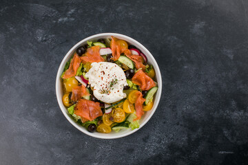 Easter brunch salad. Smoked salmon, buratta cheese, tomato, olive oil, lemon dressing salad on wooden background, top view. Flat lay