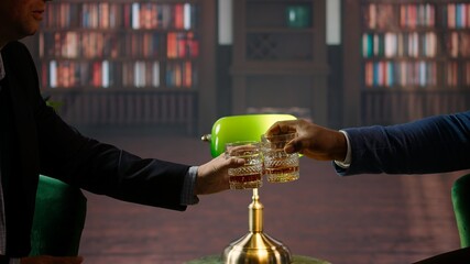 Businessmen clinking glasses of scotch and saying cheers, feeling excited about collaborating on...
