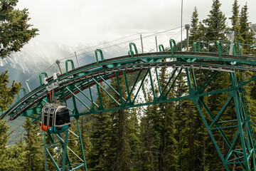 A gondola curves around green steel rails in the forest © Viks