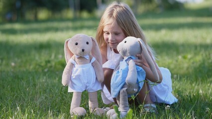 Child engages in a playful activity with plush bunnies, surrounded by green grass and sunshine,...
