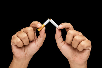 Human hand breaks a cigarette, rolled tobacco in paper with a filter tube, with a black background. Concept of no or quit smoking, a bad habit, and unhealthy