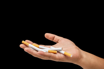 Human hand holding cigarettes, rolled tobacco in paper with a filter tube, with a black background. Concept of no or quit smoking, a bad habit, and unhealthy