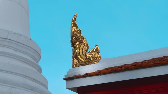 Beautiful golden chofah - traditional Thai roof decoration covered with hundreds of small golden mirrors depicts a mythical creature. Shot in motion