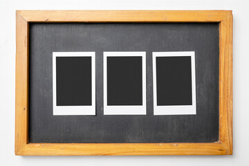 Three blank polaroid photo papers on the small blackboard on a white background. Mockup, template, or copy space. Instant camera photo print frame