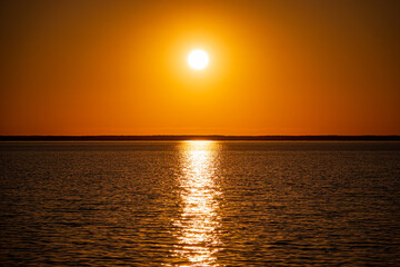 Radiant sunlight illuminates calm waters as the day transitions into a picturesque sunset