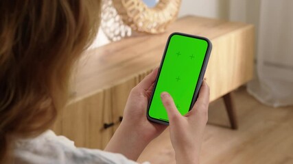 Woman sit use digital tech cell phone with green screen mock up. Hand scroll phone web site, swipe like photos. Girl hold mobile closeup. Chroma key page. Cozy home background. Online app copy space. - Powered by Adobe