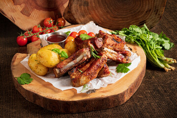 Grilled pork ribs with fresh herbs, served with colorful tomatoes and potatoes
