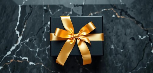 Elegant black gift box with gold ribbon on marble, top view Graduation present concept,  diploma,  gown