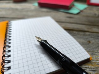Close-up of fountain pen lying on blank notepad