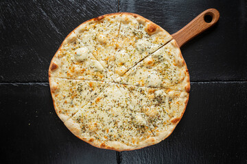 A freshly baked white pizza topped with herbs lies on a wooden paddle, inviting a tasty feast