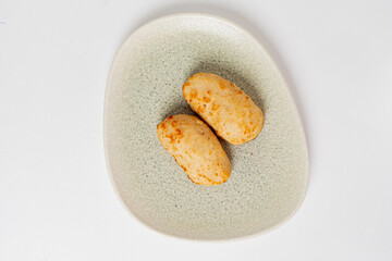 Two perfectly shaped potato croquettes lightly golden brown on a simple plate, ready to be enjoyed