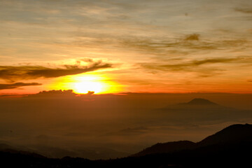 Golden sunrise over misty mountain layers with dramatic orange and yellow sky. Peaceful and atmospheric nature landscape.........