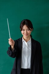 Woman teacher in front of a green board, holding a baton
