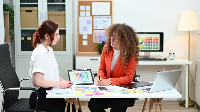 UX UI designers working with color palettes, wireframes, and digital tablets in modern office. Creative teamwork, planning, branding and design strategy