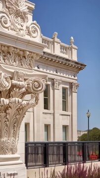 Ornate architectural stone column with acanthus leaves and scroll details with classical design elements against a bright blue sky.