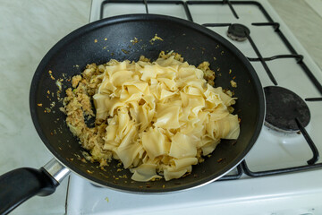 cooked pasta added to caramelized cabbage in a wok