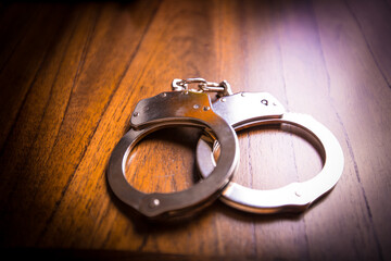 Handcuffs concept on a table with guns of different caliber