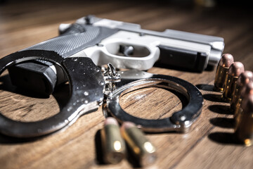 Handcuffs concept on a table with guns of different caliber