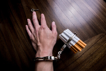 Cigarettes attached to a handcuff and hand, as in attached to your self and cant quit