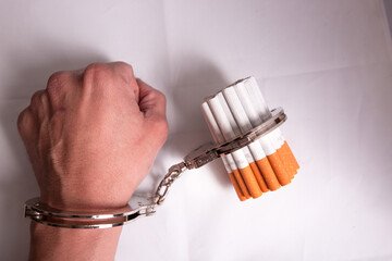 Cigarettes attached to a handcuff and hand, as in attached to your self and cant quit