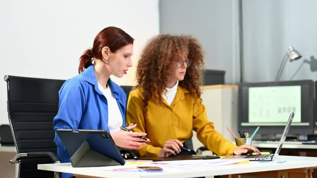 Two female fintech developers collaborating on finance apps, data analytics, and UI UX design in a high tech startup office