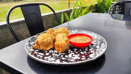 Tahu walik, tofu walik traditional Indonesian food, on a black table, aesthetic modern outdoor cafe menu, when the weather is cloudy.
