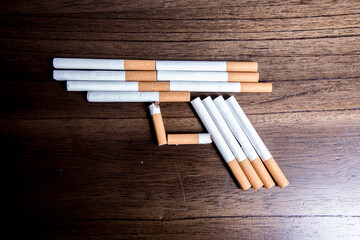 Burning cigarette with smoke and concept of cigarettes shaped as a gun to kill