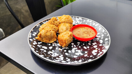 Tahu walik, tofu walik traditional Indonesian food, on a black table, aesthetic modern outdoor cafe menu, when the weather is cloudy.