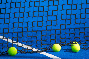 four padel balls near the net in a blue paddle tennis court, racket sport concept background