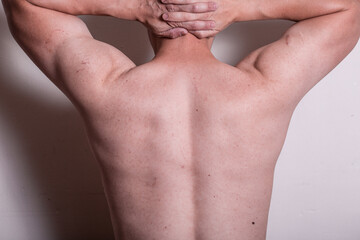 A person with no shirt with hands on head like getting arrested