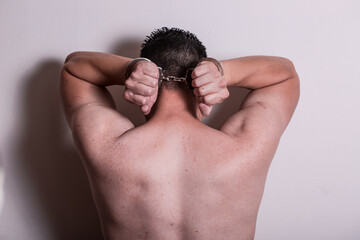 A person with no shirt with hands on head like getting arrested