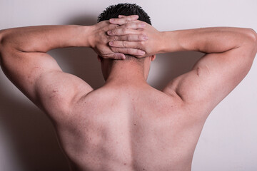 A person with no shirt with hands on head like getting arrested