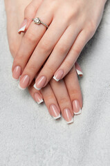 Naklejka premium Woman showing french manicure on white towel background