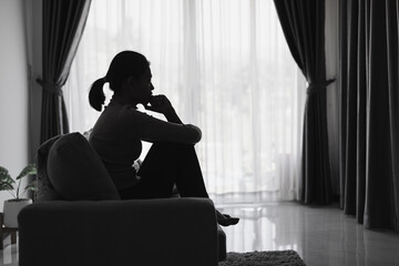 Sad and depressed woman sitting on sofa at home.Stop violence against women,  Domestic abuse victim. Suicide due to depression.
