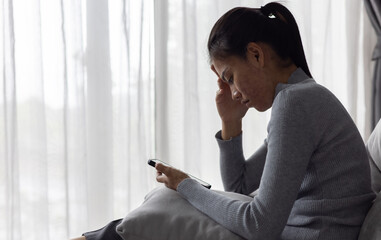 Sad and depressed woman sitting on sofa at home.Stop violence against women,  Domestic abuse victim. Suicide due to depression.