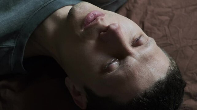 A blue-eyed young man cries. Close-up of man crying with tear rolling down cheek. A broken heart from unrequited love