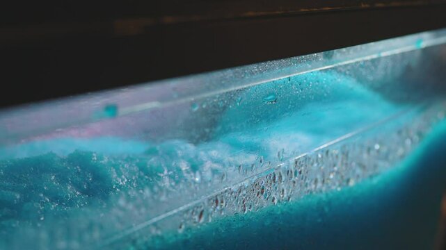 Ice sorbet machine mixing fruit juice. Crushed ice colored blue with fruit flavor. 