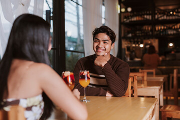 A young Southeast Asian Gen Z man leans in and smiles as he listens intently to his date, showing warmth and interest during their evening out.