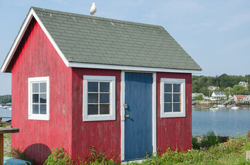 Red wooden fishing shack with a blue door against the clear blue sky on Bailey Island, Harpswell, Maine, New England, USA