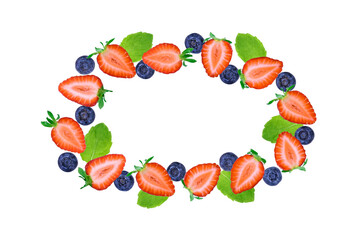 Fresh strawberry halves, blueberries and mint leaves arranged in an oval shape on white background. Healthy summer fruit frame with copy space.