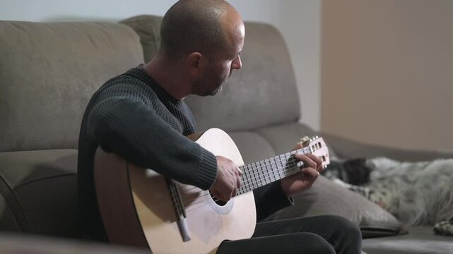 Musician playing acoustic guitar at home