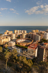 Bull Ring, Plaza la Malagueta, Andalusia, Spain. Aerial view of urban landscape featuring circular arena surrounded by modern buildings and ocean backdrop