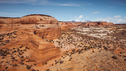 Layered Red Rock Cliffs and Snow-Capped Mountains in Utah Desert