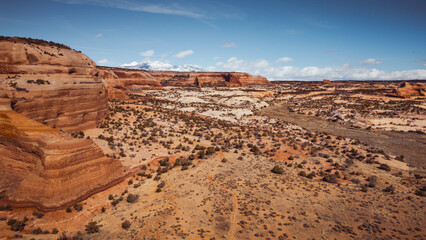 Aerial View of Red Rock Formations and Snow-Capped Mountains