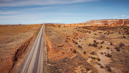 Desert highway toward red rock cliffs in Utah beneath soft blue sky