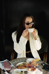 Woman in sunglasses sipping coffee outside