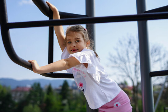 Happy child climbing on playground bars on a sunny day