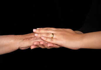 Close-up of young and elderly hands meeting in a gentle touch